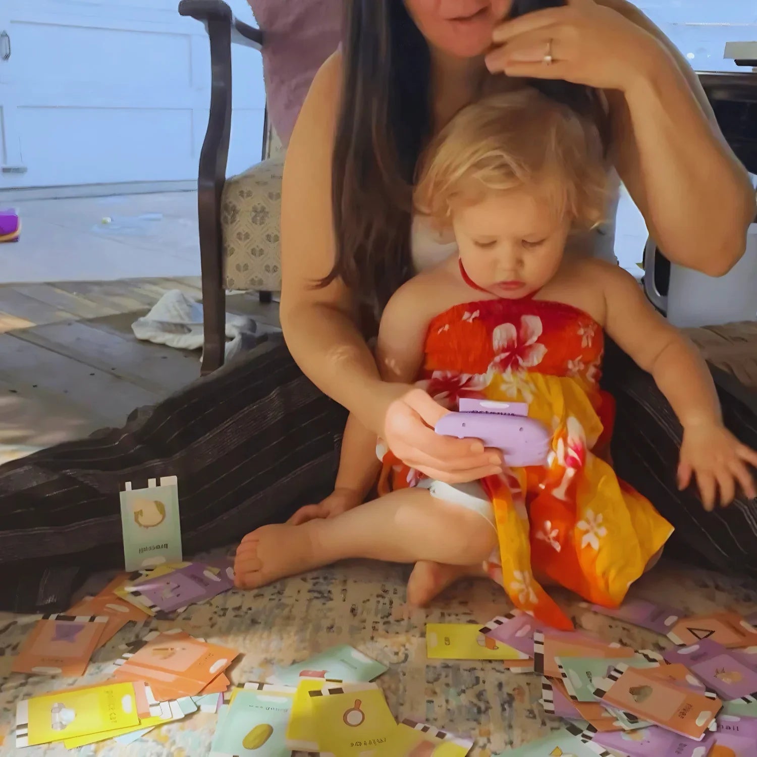 Majka i dijete zajedno koriste KinderSpeech edukativni uređaj okruženi brojnim karticama za učenje, potičući razvoj govora i rano prepoznavanje pojmova.